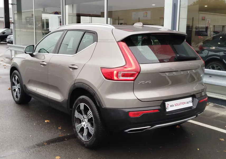 Vue 3/4 arrière droite d'un Volvo XC40 beige 2020 avec feux LED caractéristiques et jantes bi-ton.