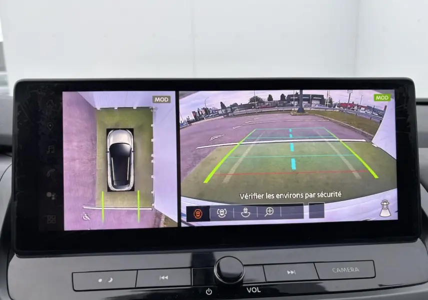 Écran multimédia affichant la caméra 360° du Nissan Qashqai blanc nacré, vue de dessus et arrière en stationnement.