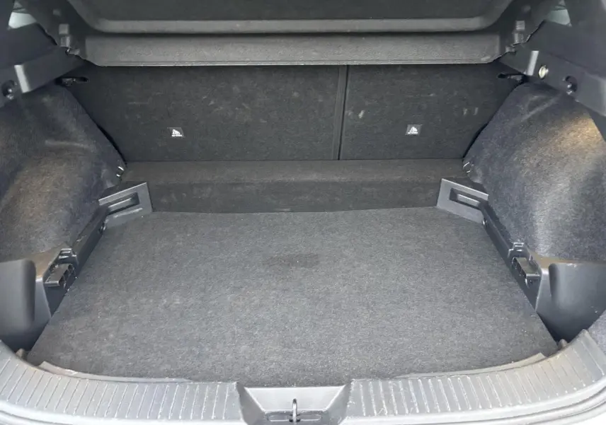 Coffre vide vu de l'arrière d'un Nissan Qashqai blanc nacré, montrant la moquette et les fixations ISOFIX.