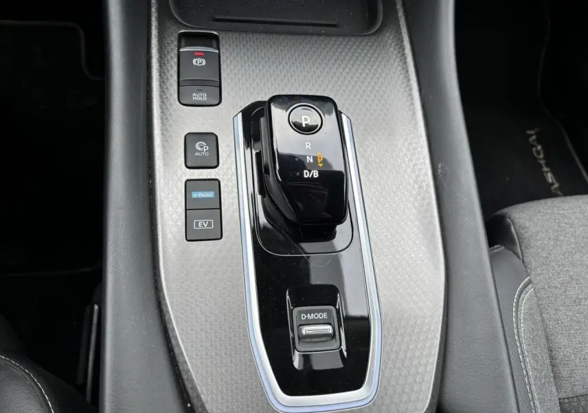 Gros plan sur la console centrale du Nissan Qashqai blanc nacré, avec levier de vitesses automatique et boutons e-Pedal et EV.