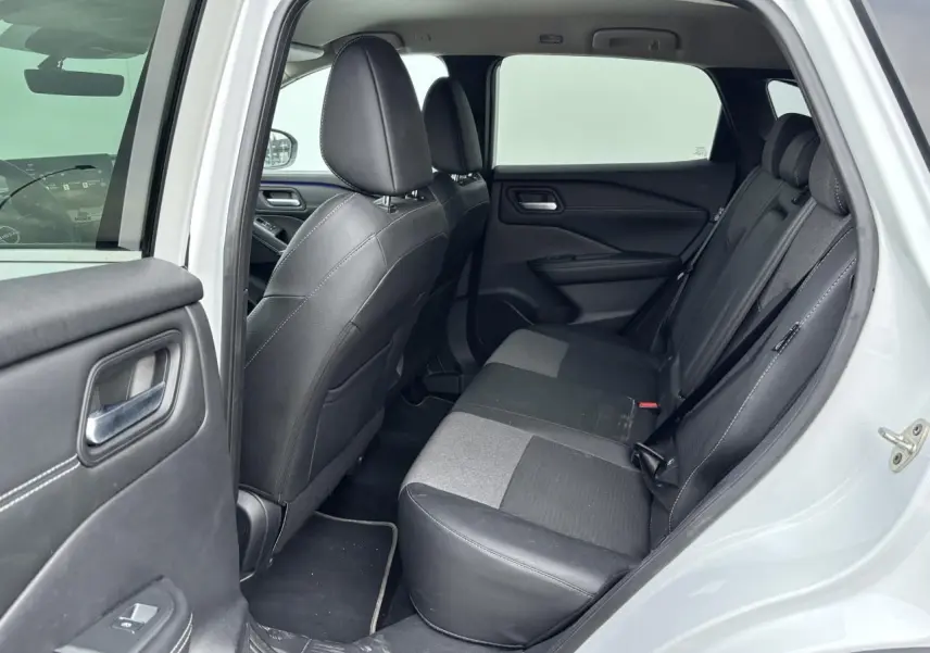 Vue intérieure côté gauche montrant la banquette arrière en sellerie mixte noir du Nissan Qashqai blanc nacré.