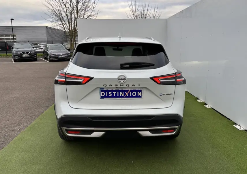 Vue arrière d'un Nissan Qashqai blanc nacré avec feux LED et logo E-POWER sur un sol vert artificiel.