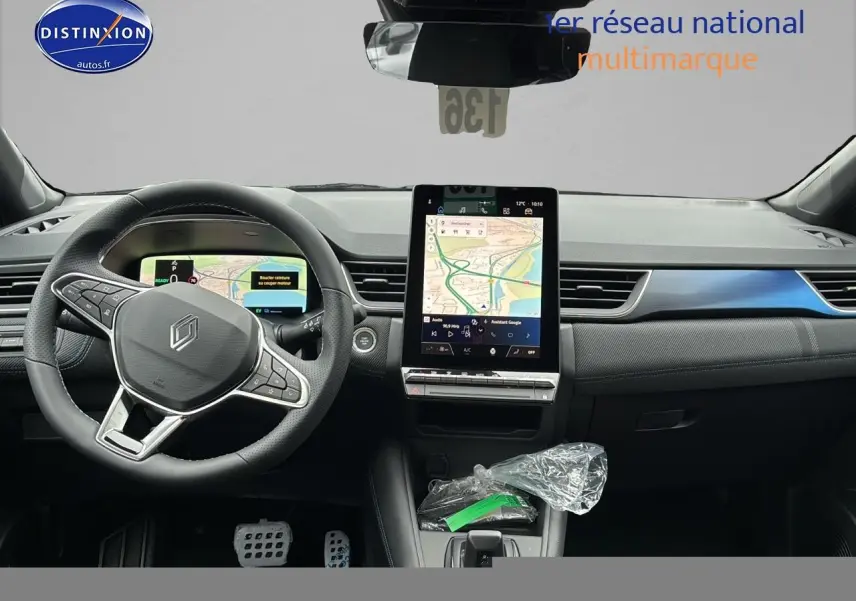 Vue intérieure avant du Renault Captur 2025 hybride, tableau de bord avec écran tactile vertical et volant multifonction cuir noir.