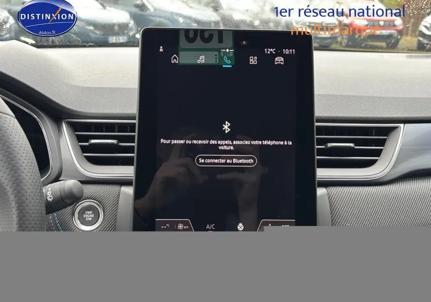 Vue intérieure centrée sur l'écran tactile du tableau de bord du Renault Captur gris rafale, avec bouton start visible.