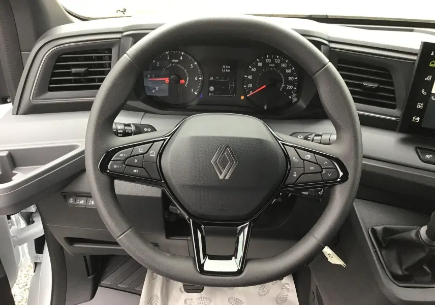 Vue rapprochée du volant noir du Renault Master blanc 2025, avec tableau de bord et commandes visibles.