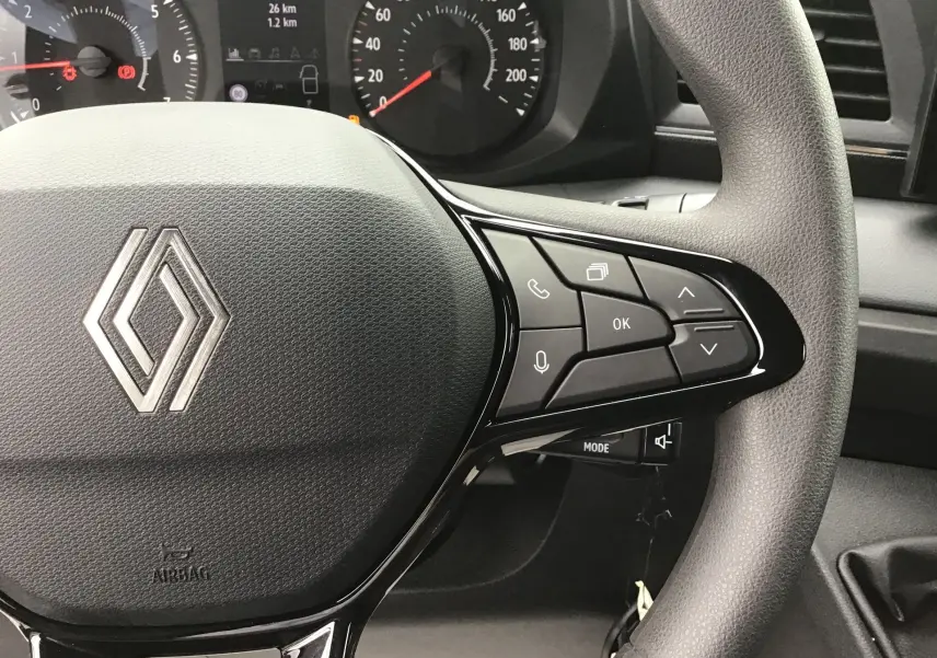 Gros plan sur le volant côté droit du Renault Master blanc 2025, avec commandes multifonctions et tableau de bord en arrière-plan.