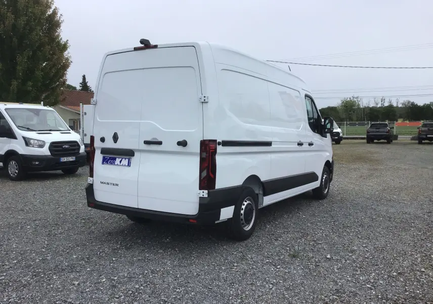 Vue 3/4 arrière droite du Renault Master blanc 2025, fourgon utilitaire avec portes arrière fermées sur parking.