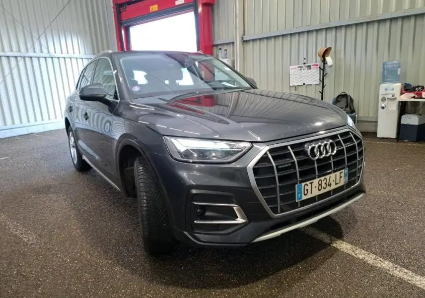 Audi Q5 gris en 3/4 avant droit, avec calandre large et jantes en alliage à 5 branches doubles.