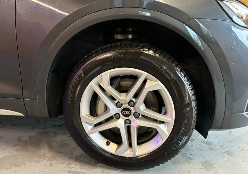 Gros plan sur la roue avant gauche gris argent avec jante aluminium 5 branches doubles d’un Audi Q5 hybride rechargeable 2024.