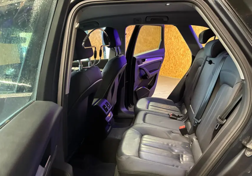 Vue intérieure arrière côté gauche d’un Audi Q5 2024 gris, montrant les sièges en cuir noir et la porte ouverte.