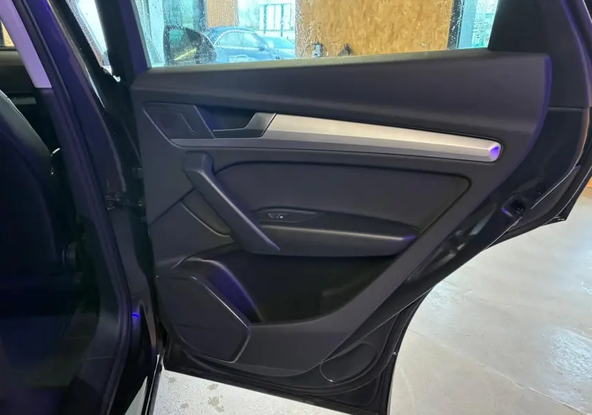 Vue intérieure de la porte arrière droite noire de l'Audi Q5 2024 avec insert argenté et haut-parleur intégré.