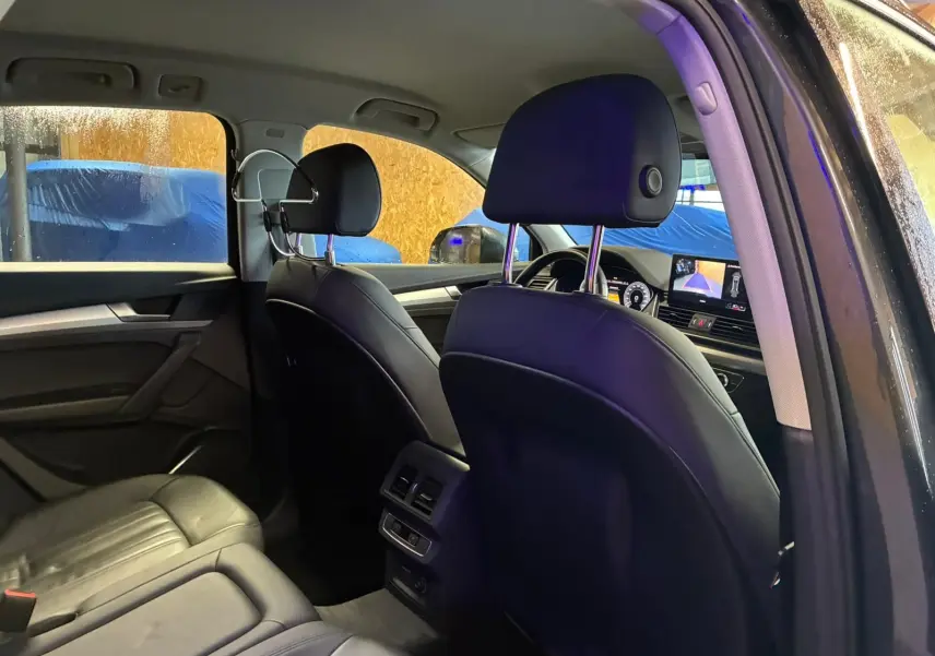 Vue intérieure arrière côté droit de l'Audi Q5 2024 gris, montrant les sièges en cuir noir et la console centrale avec commandes.