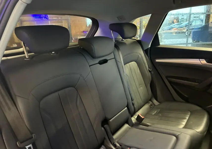 Vue intérieure sur la banquette arrière en cuir noir de l'Audi Q5 2024, avec appuie-têtes et ceintures visibles.