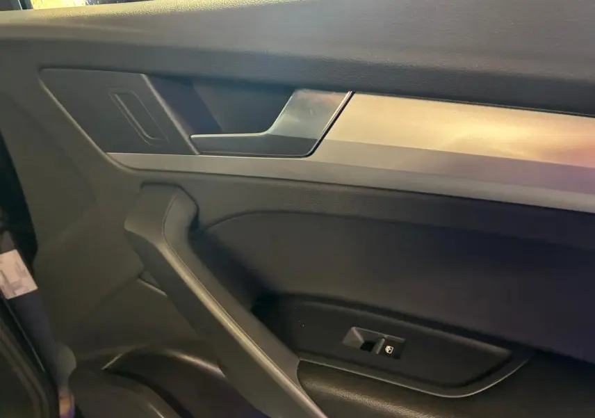 Détail de la porte intérieure côté gauche de l’Audi Q5 2024 avec insert argent et commande de vitre noire.