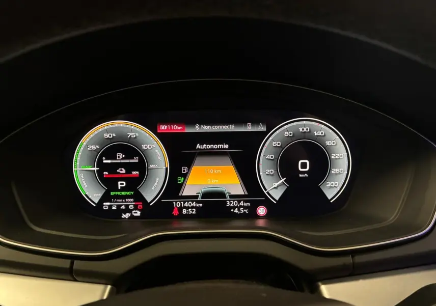 Vue rapprochée du tableau de bord numérique de l'Audi Q5 gris, affichant l'autonomie et la vitesse à 0 km/h.