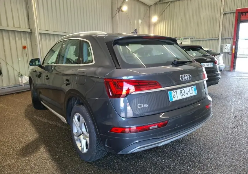 Audi Q5 gris vue de profil côté gauche dans un garage, avec jantes 5 branches doubles et moulures argentées.