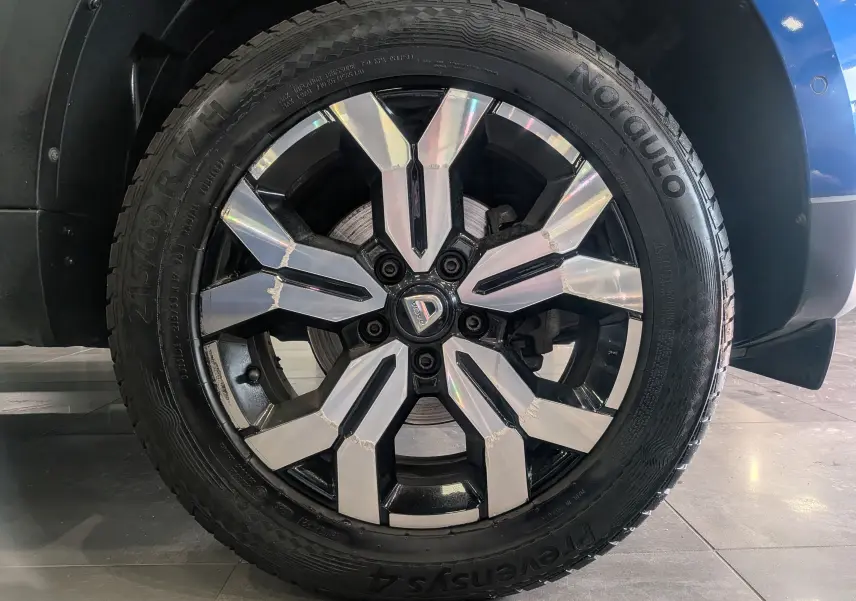 Gros plan sur la roue avant droite du Dacia Duster bleu Iron 2022 avec jante alliage bicolore et pneu Nordauto.