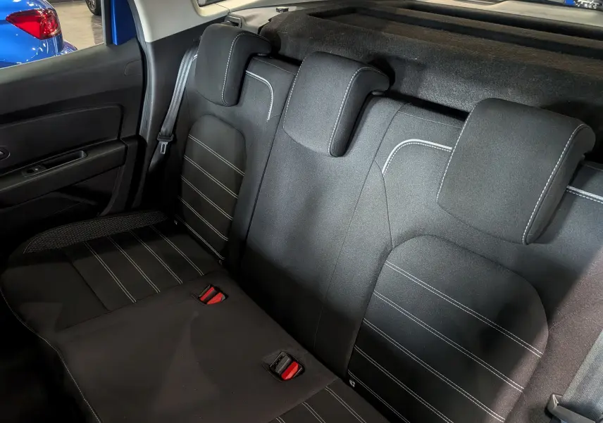 Vue intérieure sur la banquette arrière en tissu noir avec surpiqûres blanches du Dacia Duster Bleu Iron 2022.