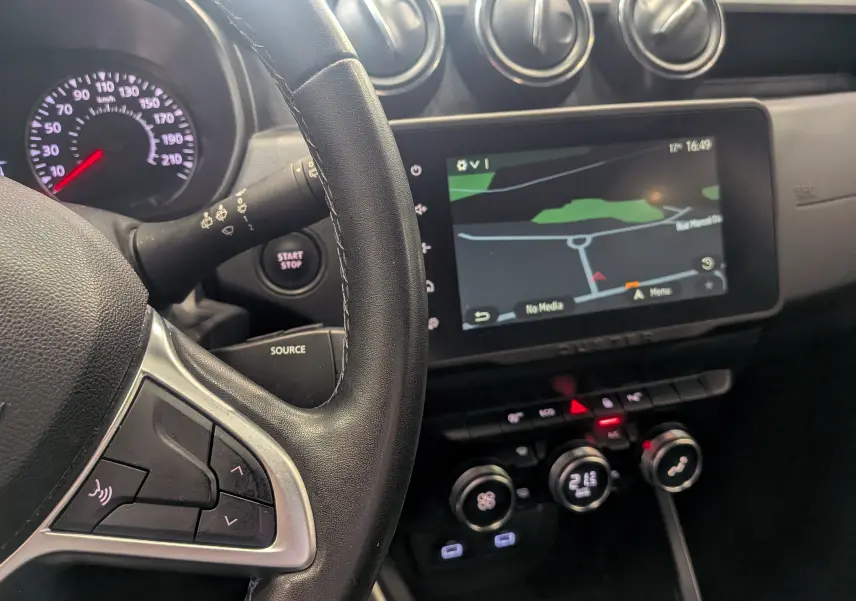 Vue rapprochée de l’intérieur du Dacia Duster 2022, tableau de bord noir avec écran tactile affichant la navigation.