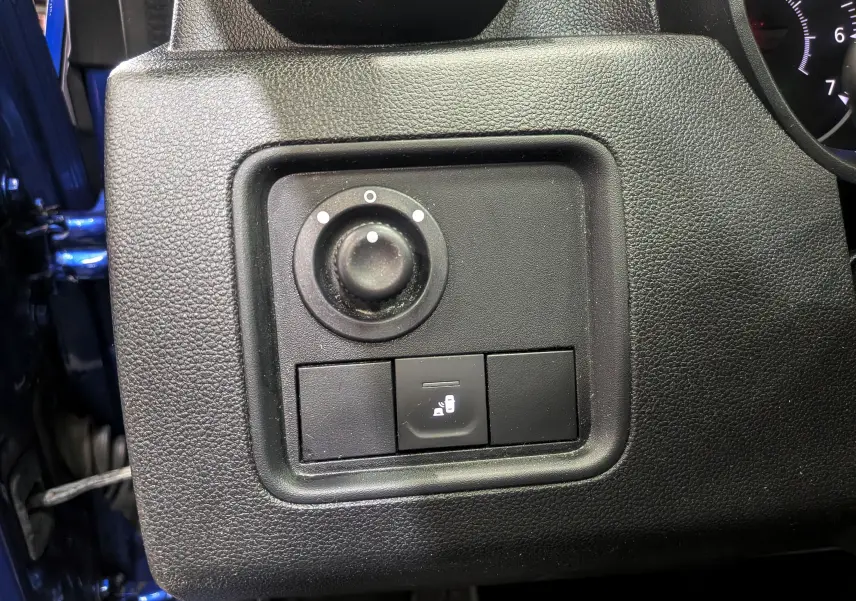 Gros plan sur le panneau de réglage des rétroviseurs et verrouillage des portes du Dacia Duster bleu Iron côté conducteur.