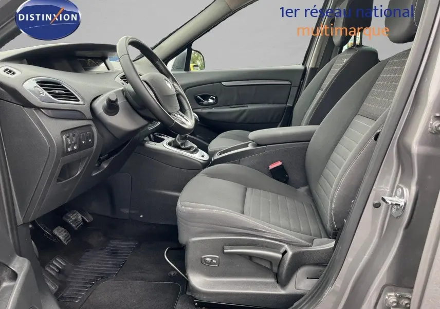 Vue intérieure côté conducteur du Renault Scénic III gris de 2015, montrant les sièges et le volant avec boîte manuelle.