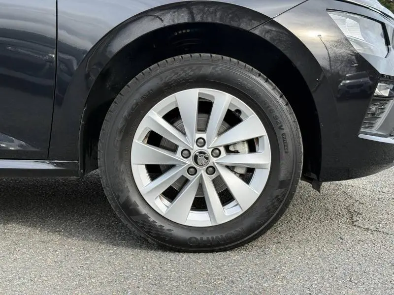 Gros plan sur la roue avant droite d’un Skoda Kamiq 2024 noir Magic nacré avec jante alliage à dix branches.