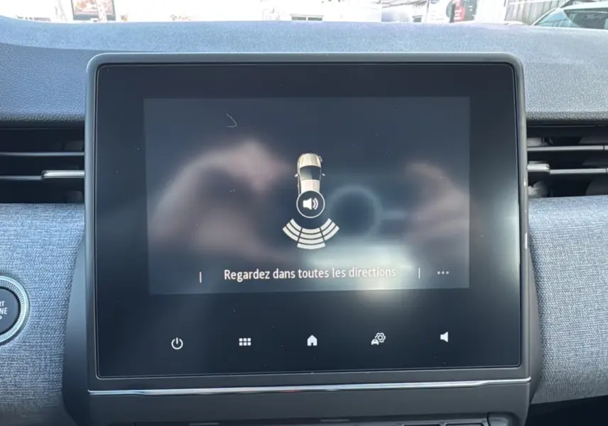 Écran tactile central de la Renault Clio gris schiste affichant une alerte de détection d'obstacles avec bouton Start/Stop visible.