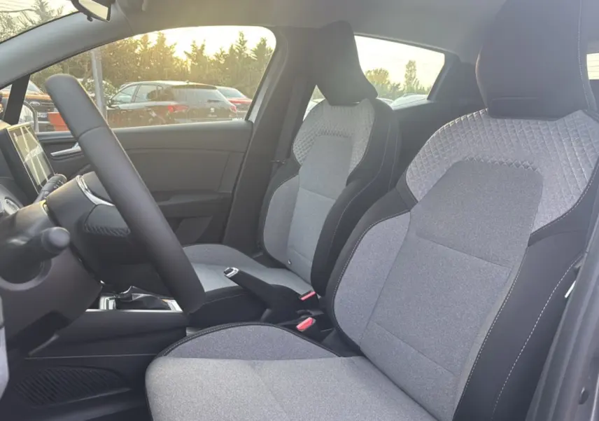Vue intérieure côté conducteur de la Renault Clio gris schiste, mettant en valeur les sièges avant en tissu bicolore.