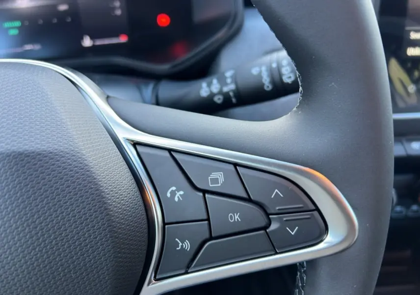 Gros plan sur les commandes multifonctions noires avec contour argenté du volant d’une Renault Clio gris schiste 2025.