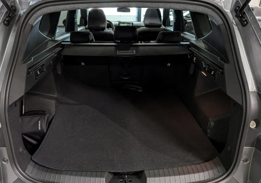 Coffre ouvert du Dacia Bigster gris schiste, vue arrière montrant l’espace de chargement et la plage arrière rétractable.