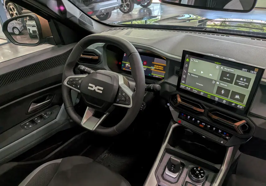 Vue intérieure côté conducteur du Dacia Bigster Hybrid-G 150 4x4 avec tableau de bord numérique et écran tactile central.