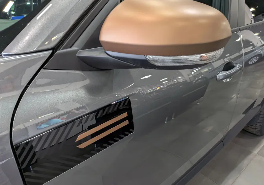 Gros plan sur le rétroviseur bronze et la portière gris schiste côté gauche du Dacia Bigster Hybrid-G 150 4x4 Extrême 2026.