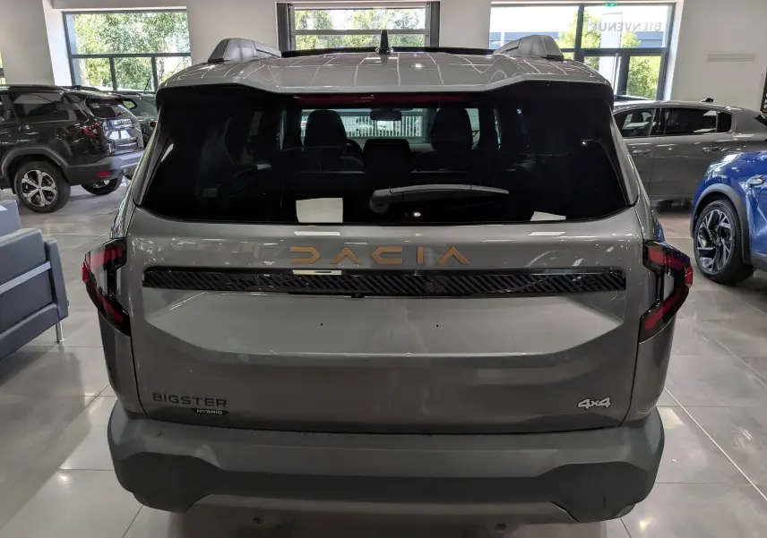 Vue arrière du Dacia Bigster Hybrid-G 150 4x4 gris schiste, avec logo Dacia doré et feux arrière LED distinctifs.