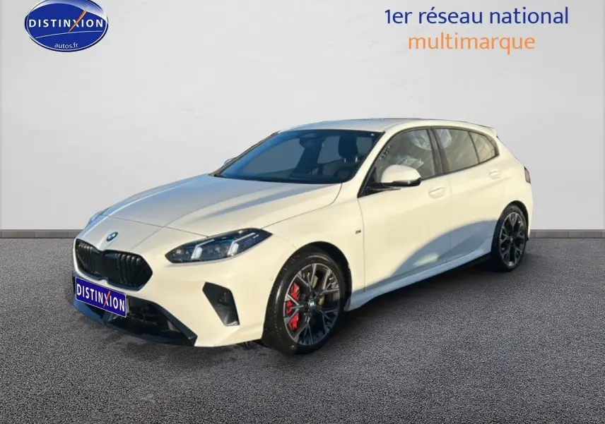 BMW Série 1 blanche alpin vue 3/4 avant droit, jantes 18 pouces bicolores et étriers de frein rouges visibles.