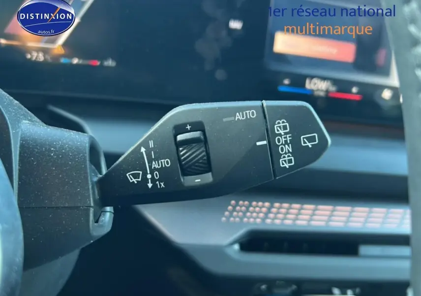 Gros plan sur la commande des essuie-glaces dans l'habitacle d'une BMW Série 1 blanche, tableau de bord en arrière-plan.