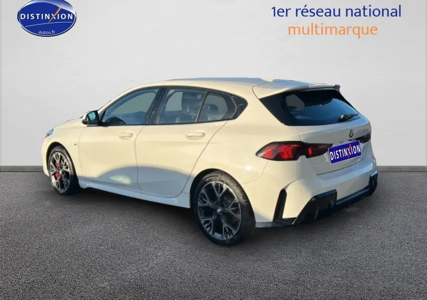 BMW Série 1 blanche alpin vue 3/4 arrière droit, jantes 18 pouces bicolores et feux arrière LED distinctifs.