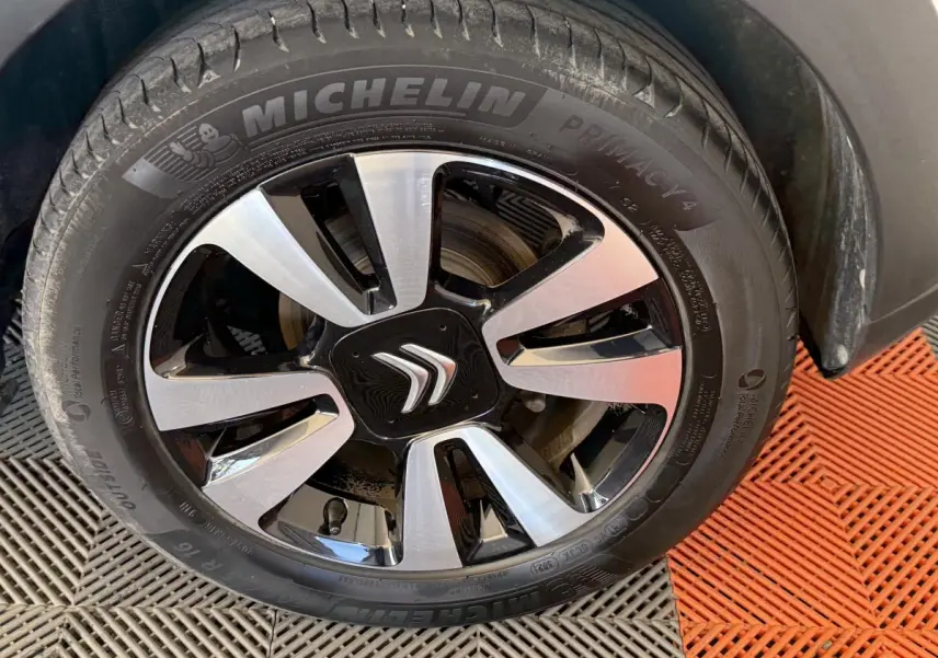 Gros plan sur la roue avant droite de la Citroën C3 blanche, avec jante alliage bicolore et logo Citroën central.