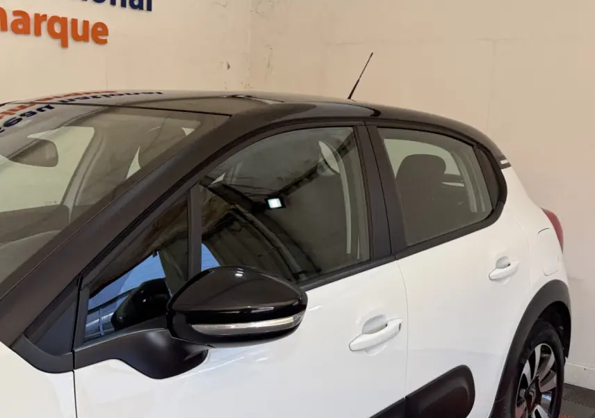 Vue côté droit arrière d'une Citroën C3 blanche avec toit noir et rétroviseur noir brillant.