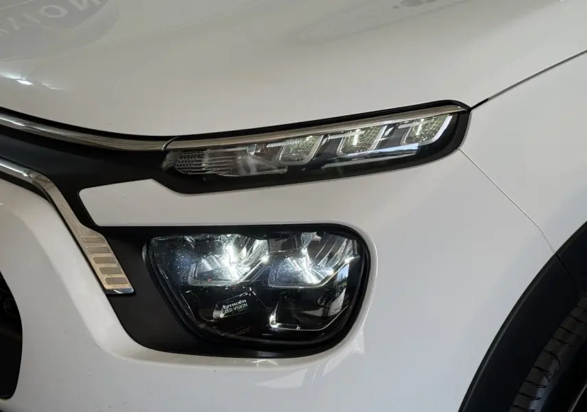 Gros plan sur le phare avant droit blanc de la Citroën C3 2021 avec feux LED distinctifs et détails chromés.
