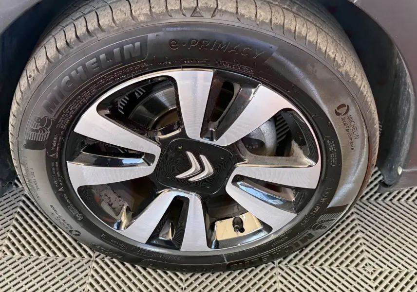 Gros plan sur la roue avant droite d'une Citroën C3 blanche, avec jante alliage bicolore et pneu Michelin e-Primacy.