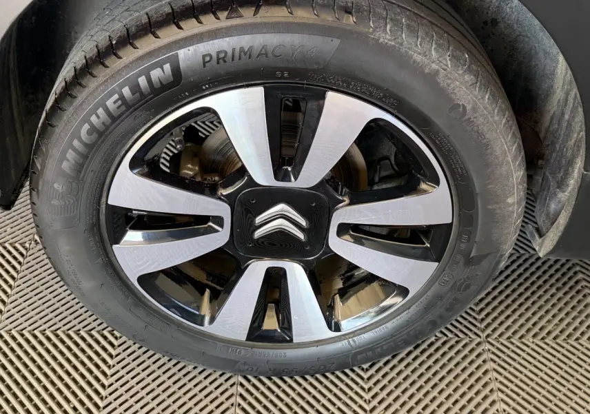 Gros plan sur la roue avant droite d'une Citroën C3 blanche, jante alliage bicolore avec logo Citroën central.