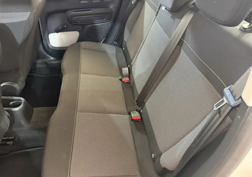 Vue intérieure sur la banquette arrière côté droit de la Citroën C3 blanche avec sièges tissu gris et ceintures noires.