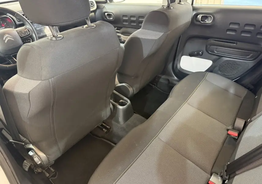 Vue intérieure arrière côté droit de la Citroën C3 blanche 2021, montrant les sièges tissu gris et la porte avec inserts blancs.