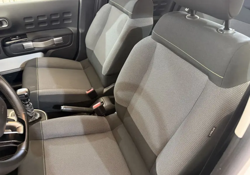 Vue intérieure rapprochée des sièges avant gris et noir de la Citroën C3 2021 avec levier de vitesse manuel visible.