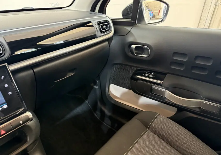 Vue intérieure côté passager de la Citroën C3 blanche 2021, avec tableau de bord noir brillant et porte au design original.