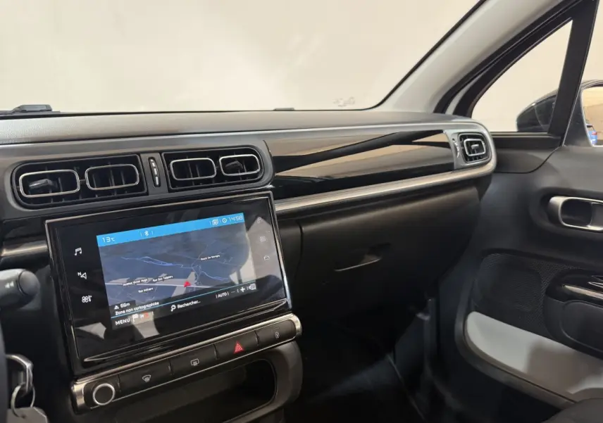 Vue intérieure côté passager du tableau de bord noir brillant et écran tactile 7 pouces de la Citroën C3 blanche 2021.