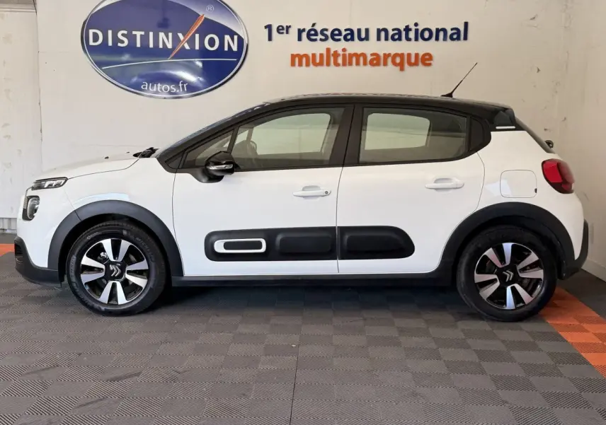 Vue de profil côté gauche d'une Citroën C3 blanche 2021 avec protections noires sur les portières et jantes bicolores.