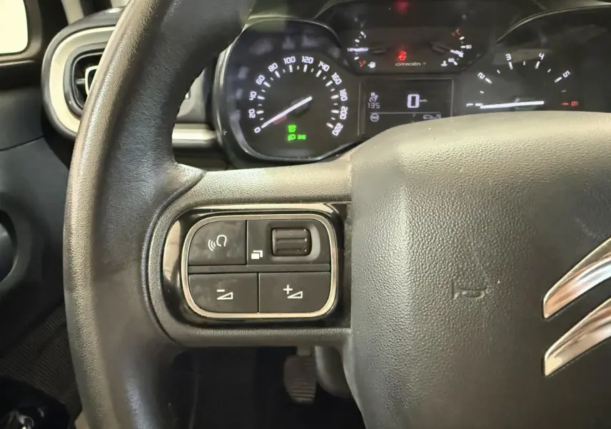 Gros plan sur le volant noir de la Citroën C3 2021 avec commandes intégrées et tableau de bord éclairé en arrière-plan.