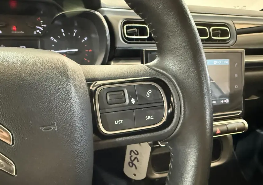 Gros plan sur le volant cuir noir de la Citroën C3 2021 avec commandes audio et écran tactile central en arrière-plan.