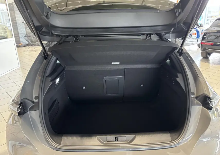 Coffre ouvert vu de l'arrière d'une Peugeot 308 gris selenium, montrant un espace de chargement vide et propre.